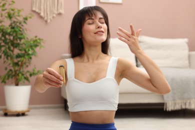 Photo of Woman with palo santo stick meditating at home, selective focus