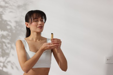 Woman with smoldering palo santo stick at home, space for text