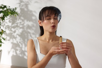 Woman with smoldering palo santo stick at home