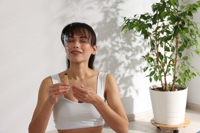 Photo of Woman with smoldering palo santo stick at home