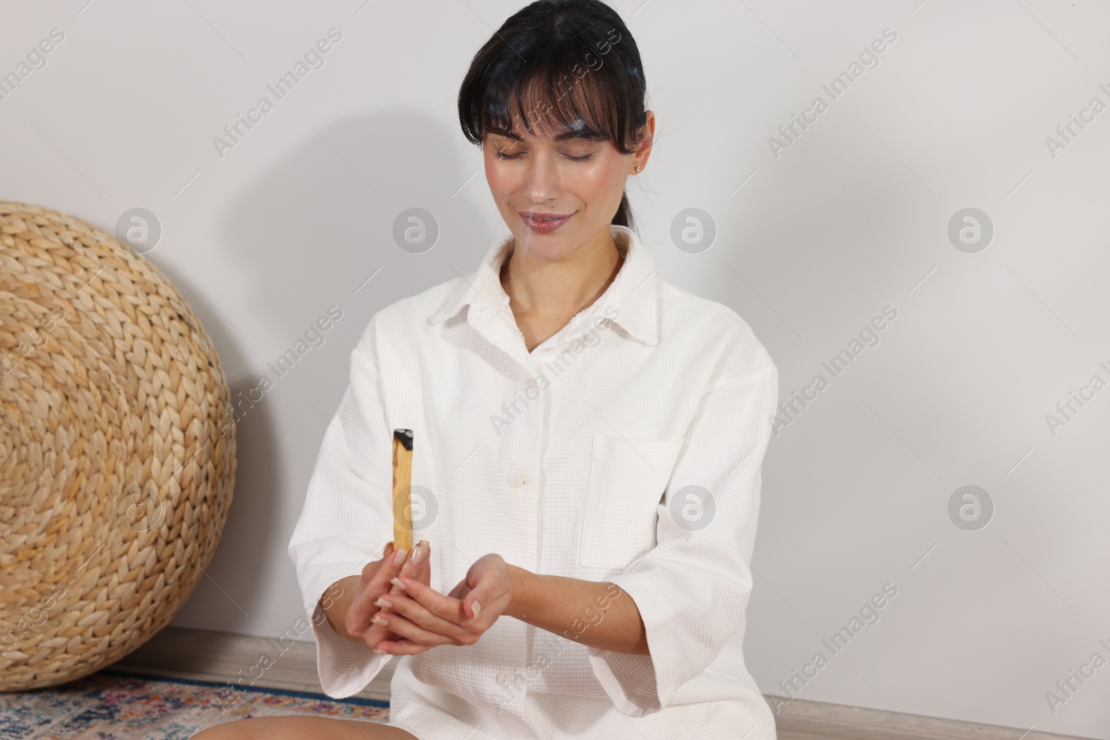 Photo of Woman with smoldering palo santo stick at home