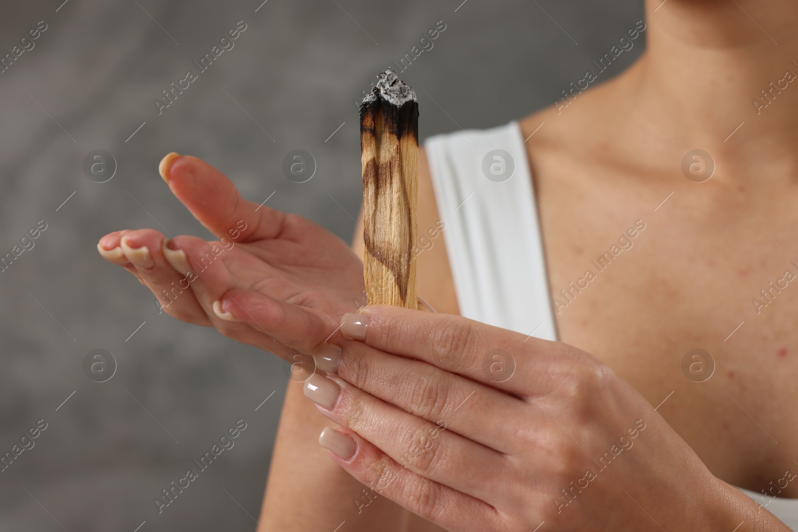 Photo of Woman with burnt palo santo stick at home, closeup