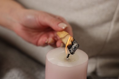 Photo of Woman lighting palo santo stick at home, closeup