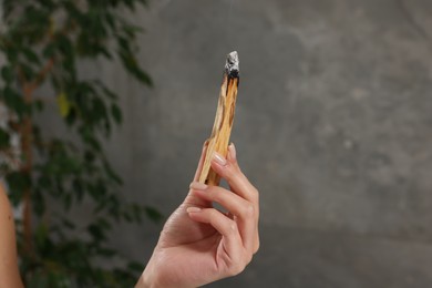 Photo of Woman with smoldering palo santo stick at home, closeup