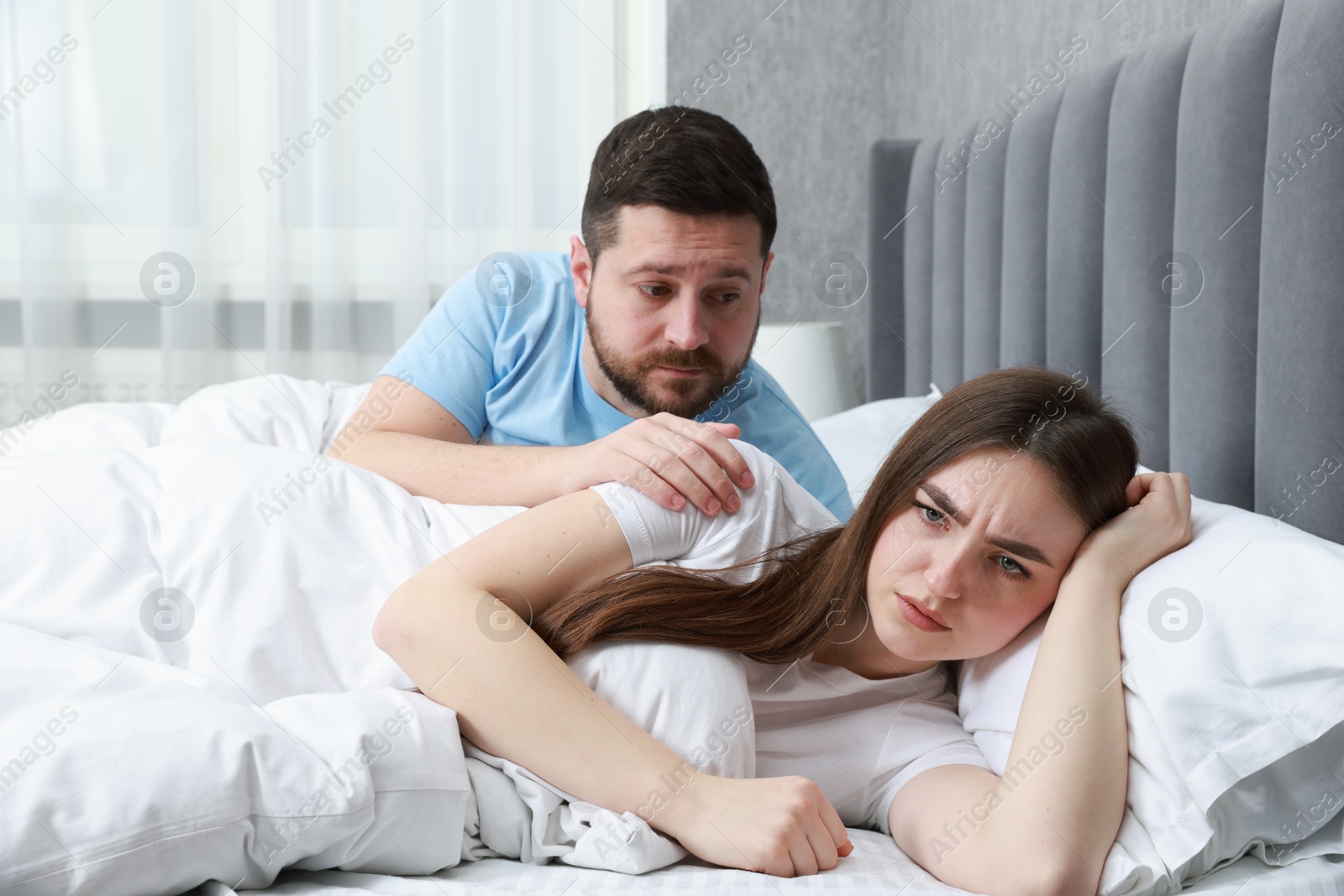 Photo of Man comforting his resentful girlfriend on bed at home