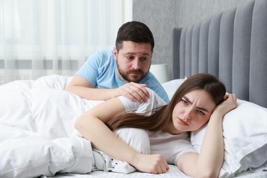 Man comforting his resentful girlfriend on bed at home