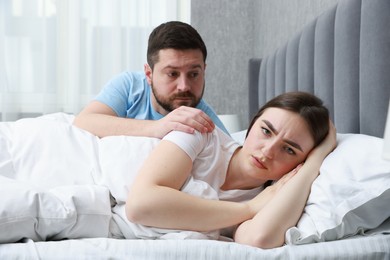 Man comforting his resentful girlfriend on bed at home