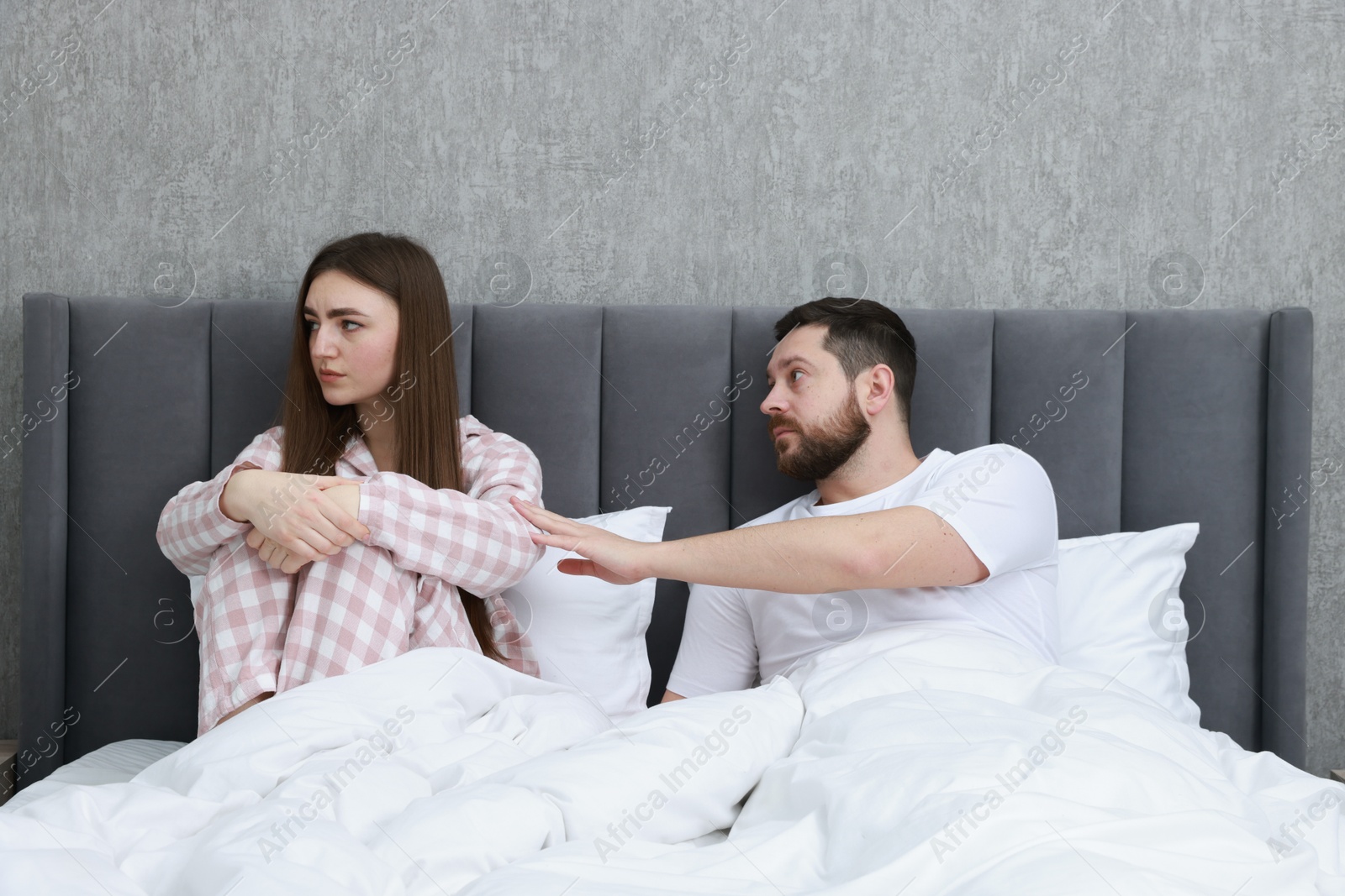 Photo of Man comforting his resentful girlfriend on bed at home