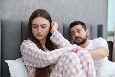 Photo of Man comforting his resentful girlfriend on bed at home, selective focus