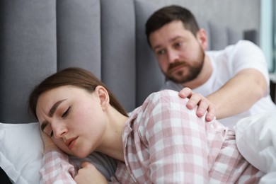 Photo of Man comforting his resentful girlfriend on bed at home, selective focus