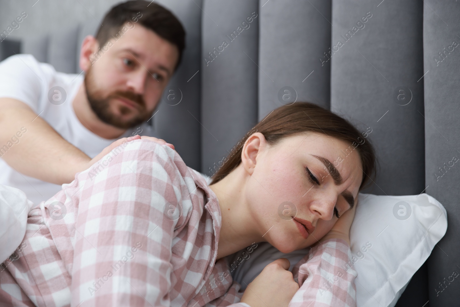 Photo of Man comforting his resentful girlfriend on bed at home, selective focus