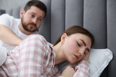 Man comforting his resentful girlfriend on bed at home, selective focus