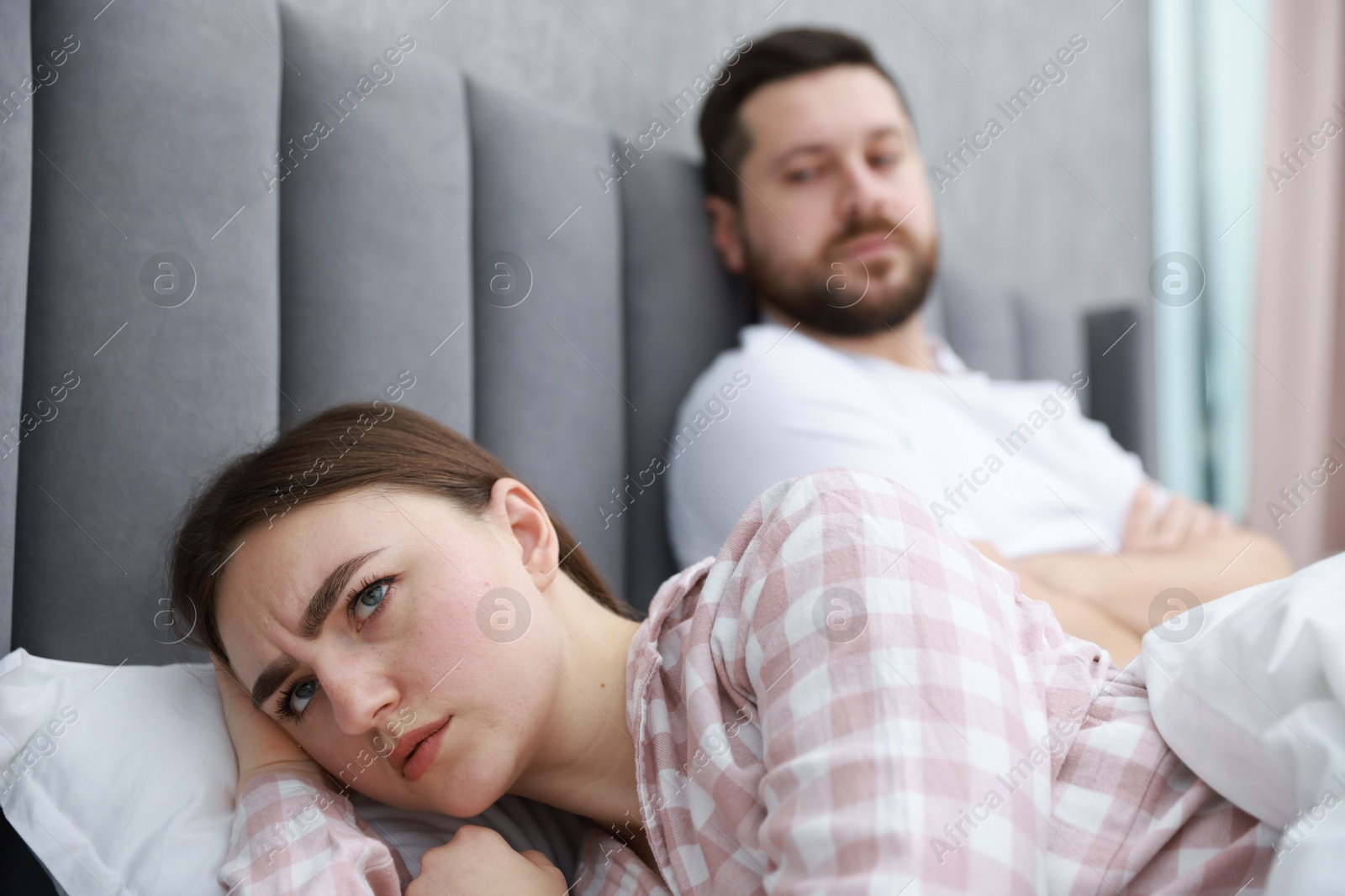 Photo of Resentful couple lying on bed at home, selective focus