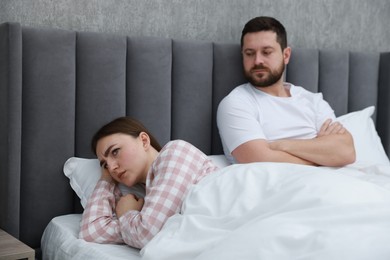 Photo of Resentful couple lying on bed at home, selective focus