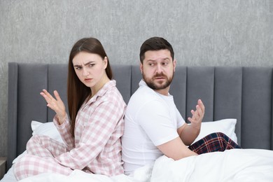 Resentful couple sitting on bed and arguing at home