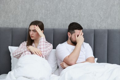 Resentful couple lying on bed at home