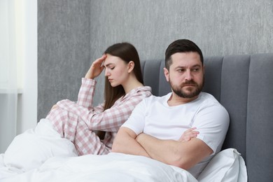 Photo of Resentful couple lying on bed at home