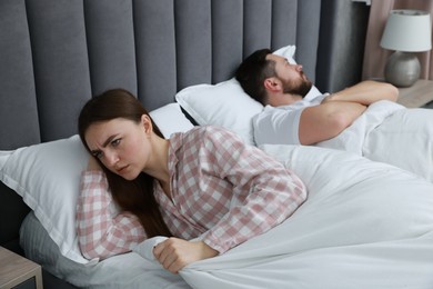 Resentful couple lying on bed at home, selective focus