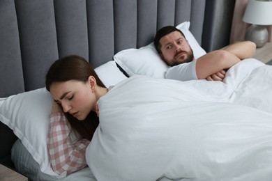 Resentful couple lying on bed at home, selective focus