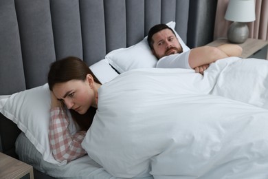 Photo of Resentful couple lying on bed at home, selective focus