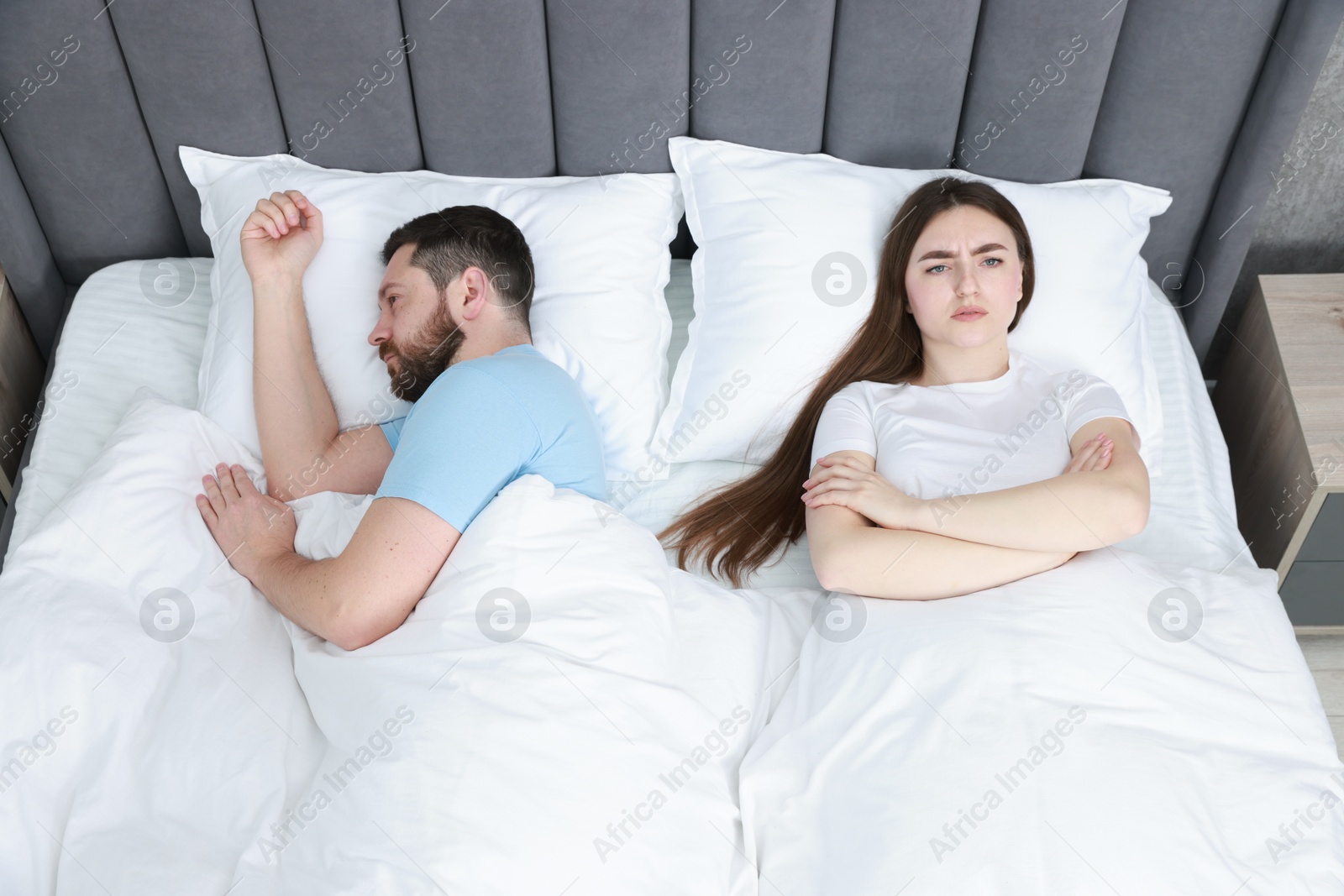 Photo of Resentful couple lying on bed at home, above view