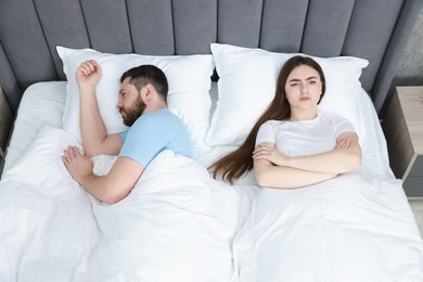 Resentful couple lying on bed at home, above view