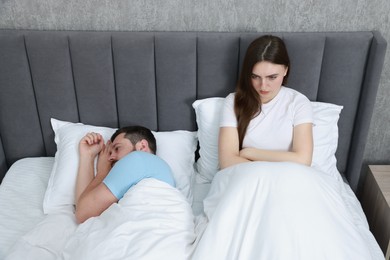 Resentful couple lying on bed at home, above view