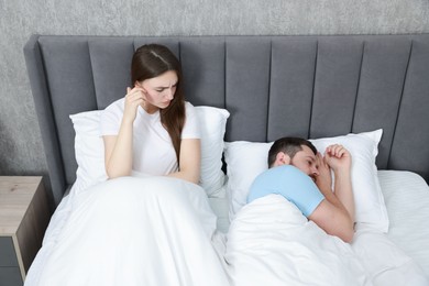 Resentful couple lying on bed at home, above view