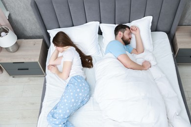 Resentful couple lying on bed at home, above view