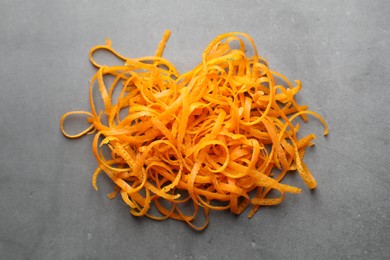 Photo of Pile of fresh orange zest on grey textured table, above view