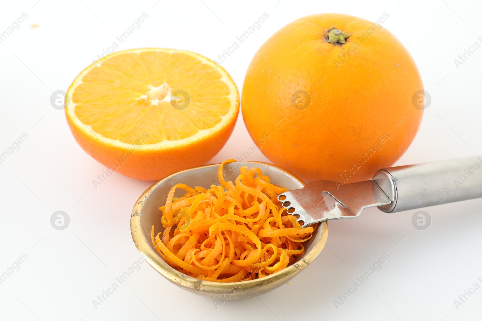 Photo of Fresh orange zest in bowl, fruits and zester on white background