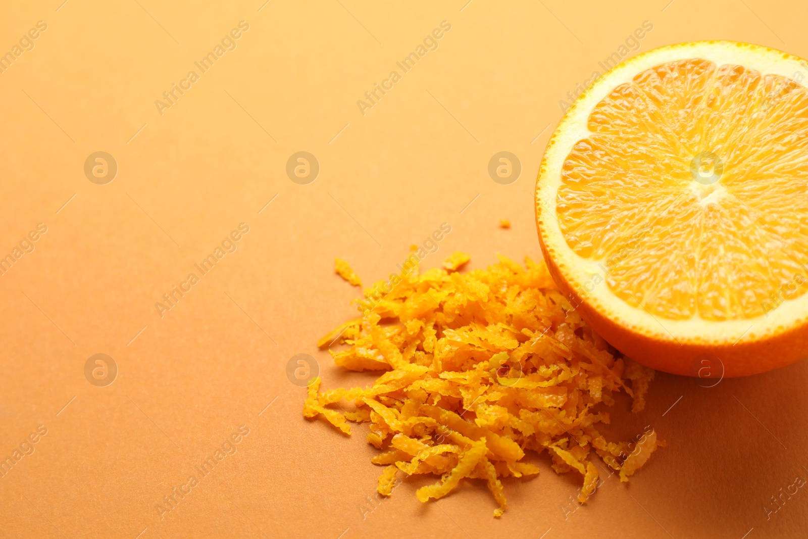 Photo of Pile of fresh orange zest and cut fruit on color background, closeup. Space for text