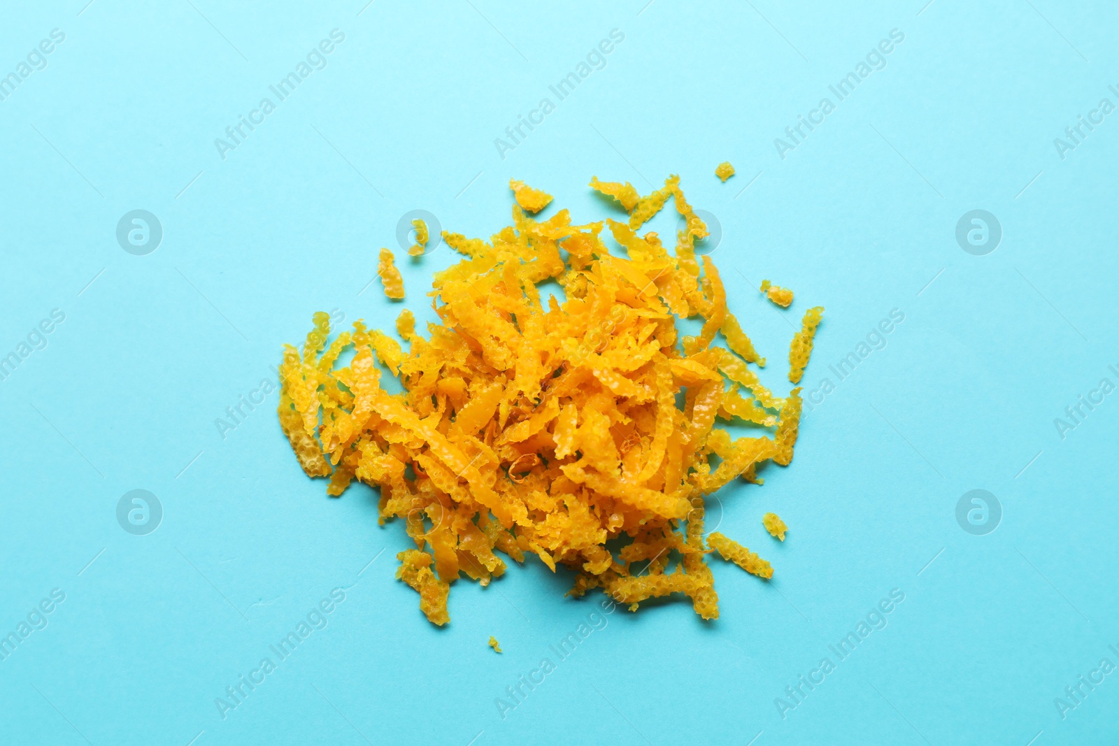 Photo of Pile of fresh orange zest on light blue background, top view