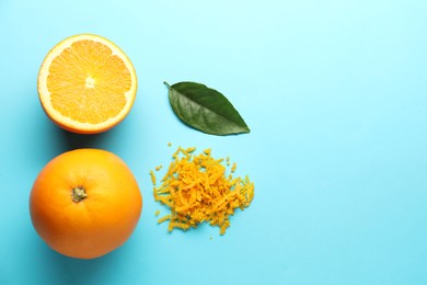 Photo of Pile of fresh orange zest, fruits and leaf on light blue background, flat lay. Space for text