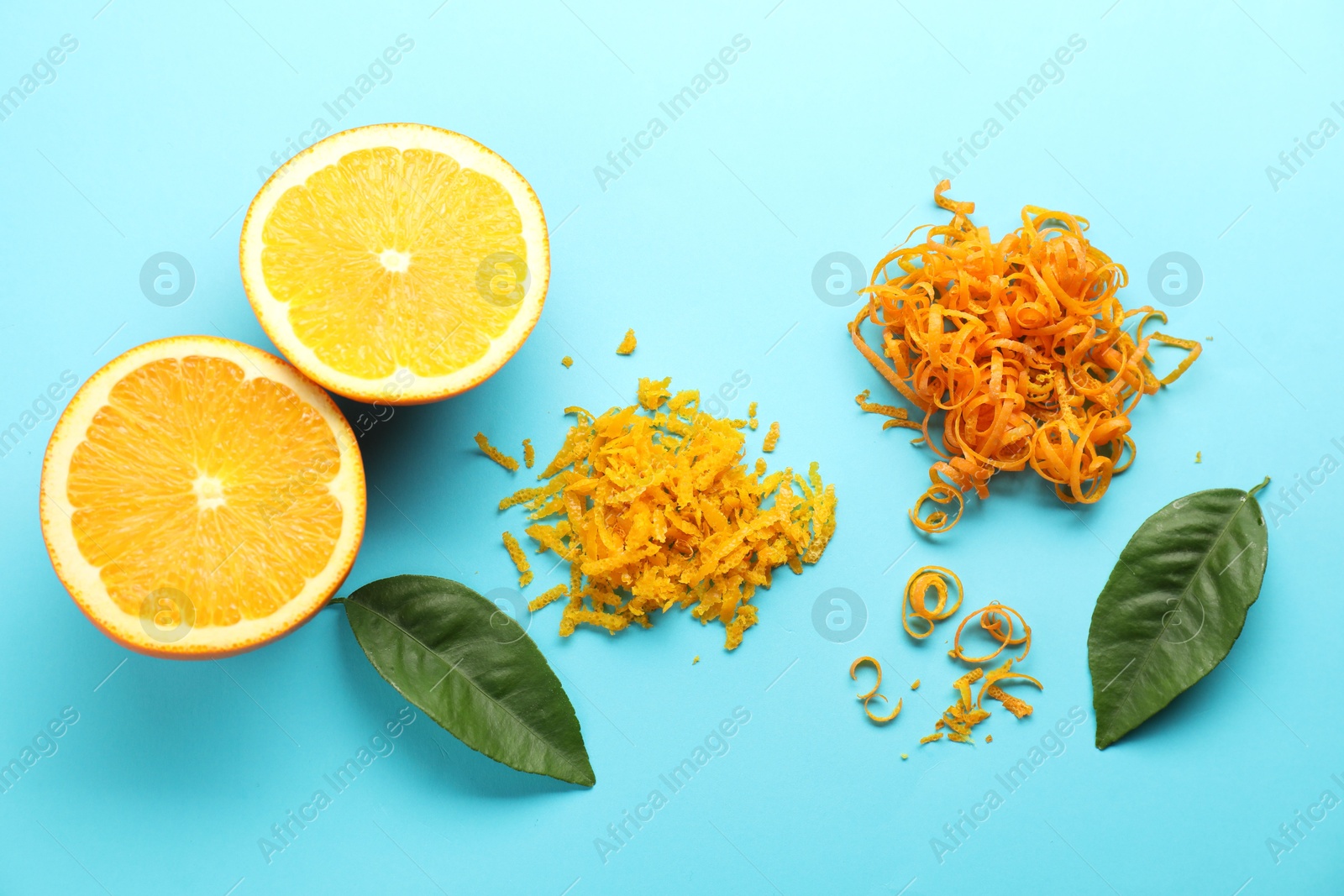 Photo of Flat lay composition with fresh orange zest, fruit and leaves on light blue background