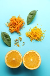 Photo of Flat lay composition with fresh orange zest, fruit and leaves on light blue background