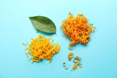 Photo of Flat lay composition with fresh orange zest and leaf on light blue background