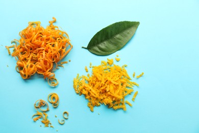 Photo of Flat lay composition with fresh orange zest and leaf on light blue background