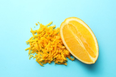 Photo of Pile of fresh orange zest and cut fruit on light blue background, top view