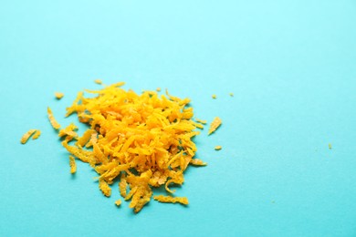 Photo of Pile of fresh orange zest on turquoise background, closeup. Space for text