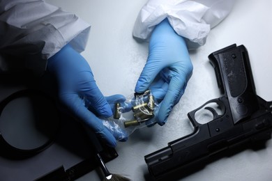 Photo of Forensic expert examining shell casings in plastic bag at table, top view