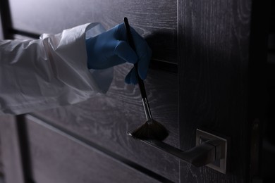 Photo of Forensic expert taking fingerprints with brush from handle of door, closeup