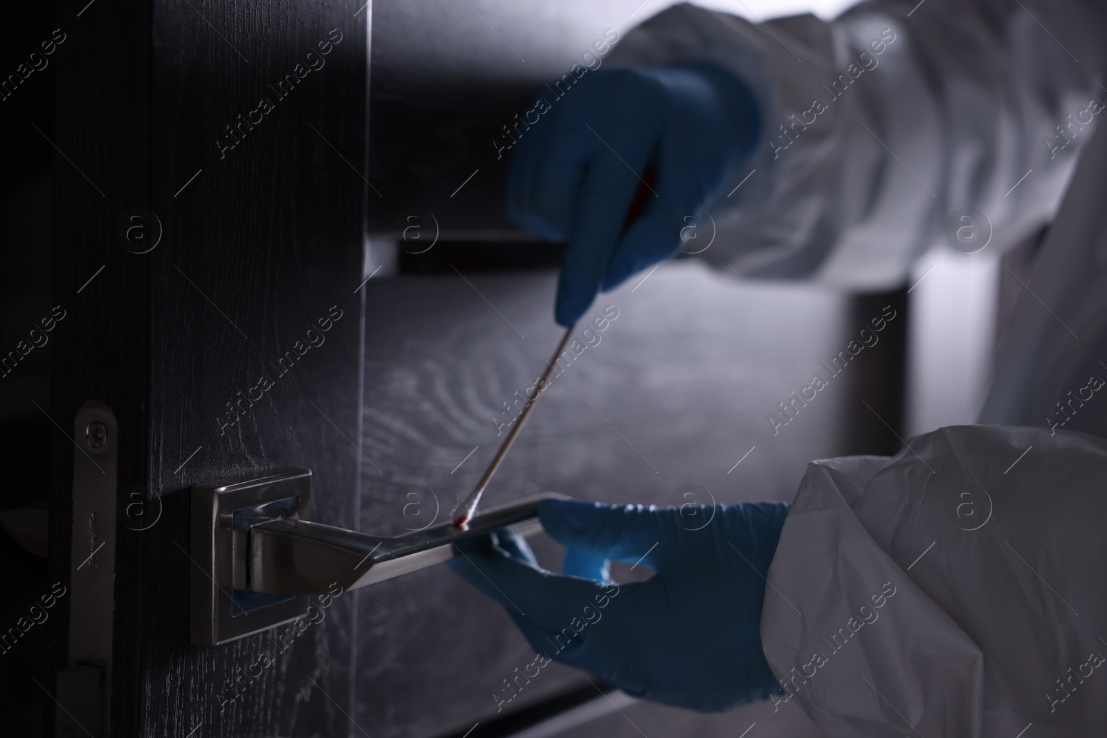 Photo of Forensic expert taking blood sample from handle of door, closeup