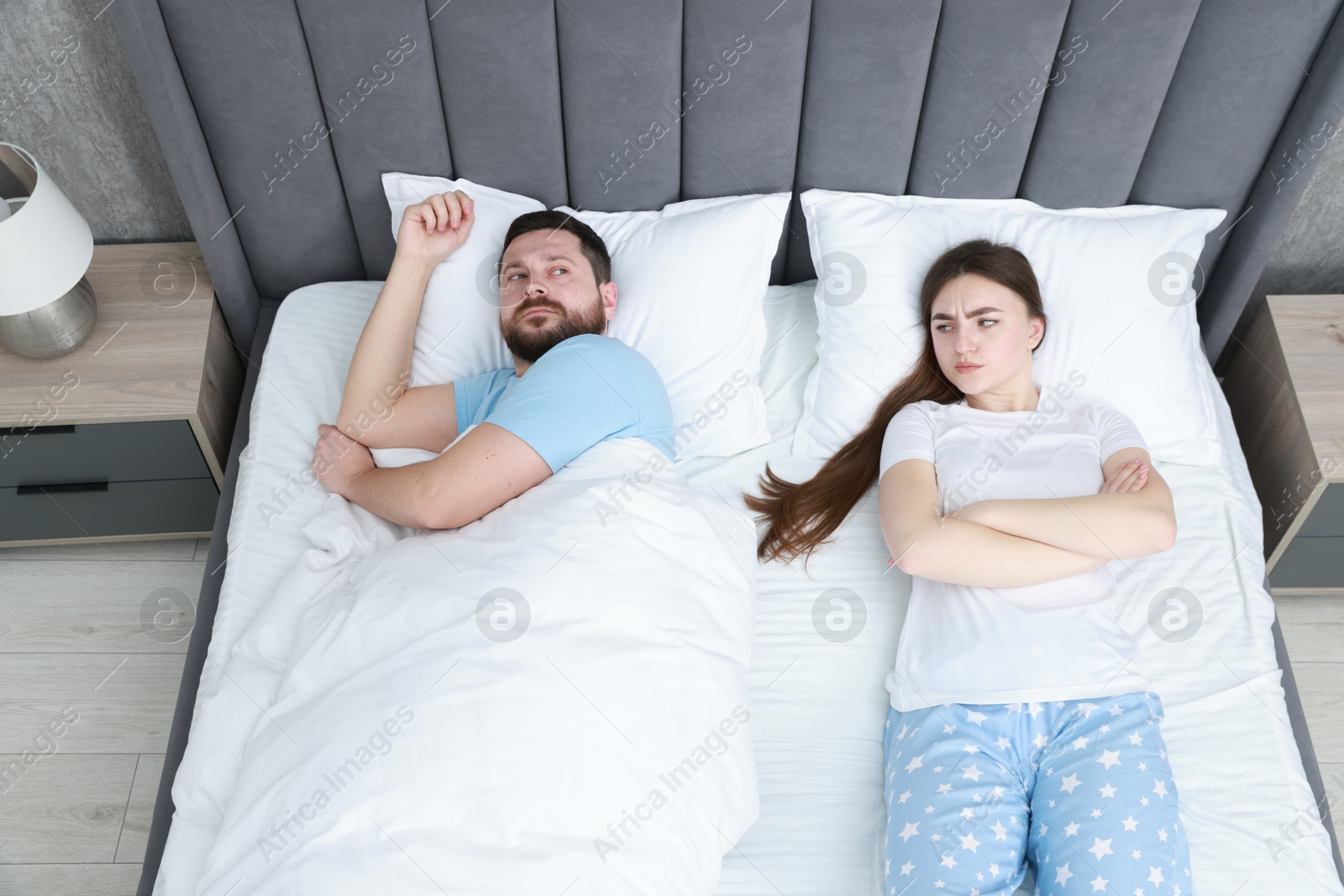 Photo of Resentful couple lying on bed at home, above view