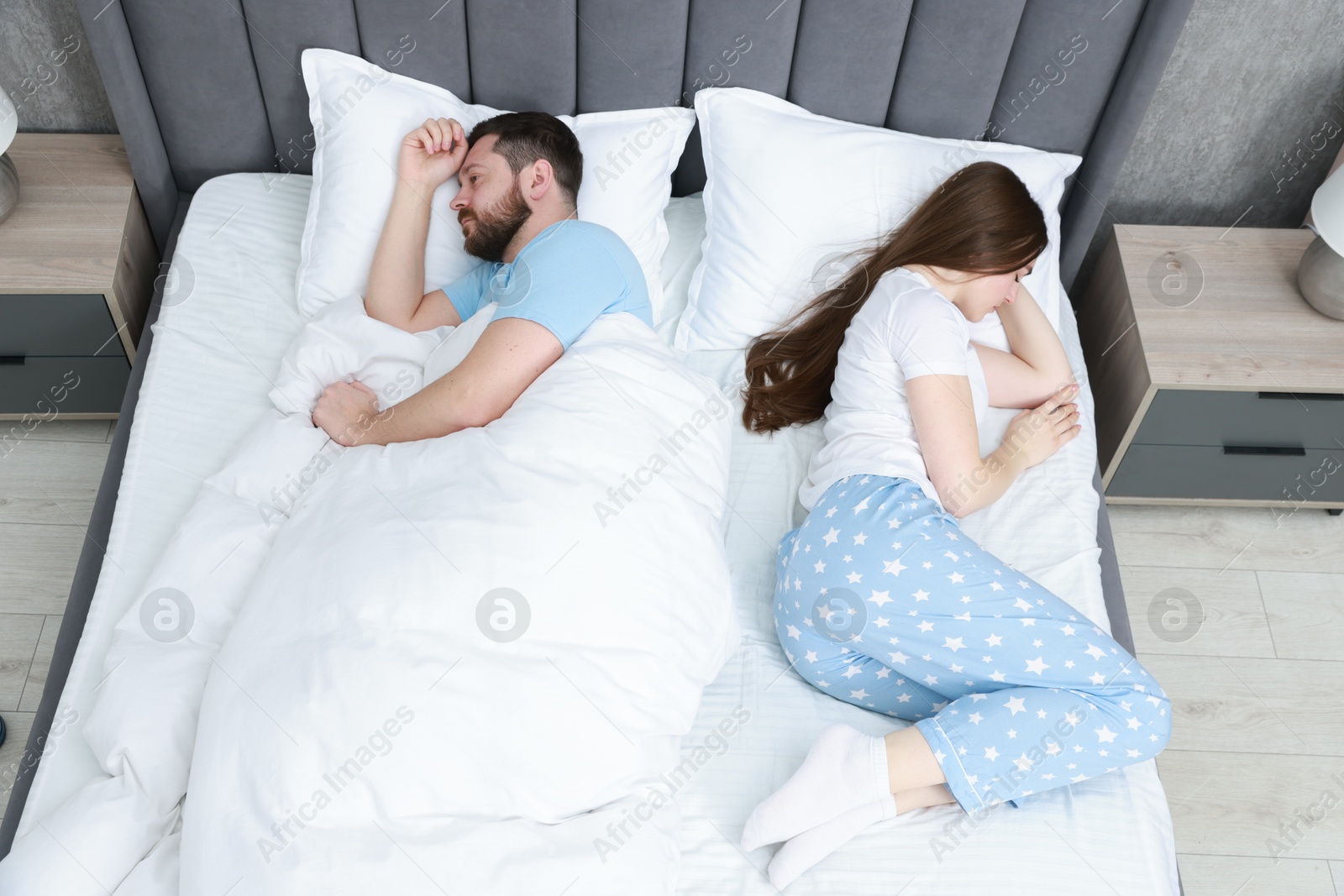 Photo of Resentful couple lying on bed at home, above view