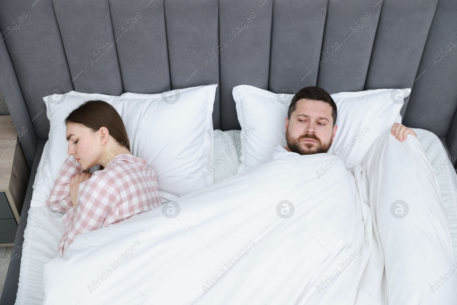 Photo of Resentful couple lying on bed at home, above view