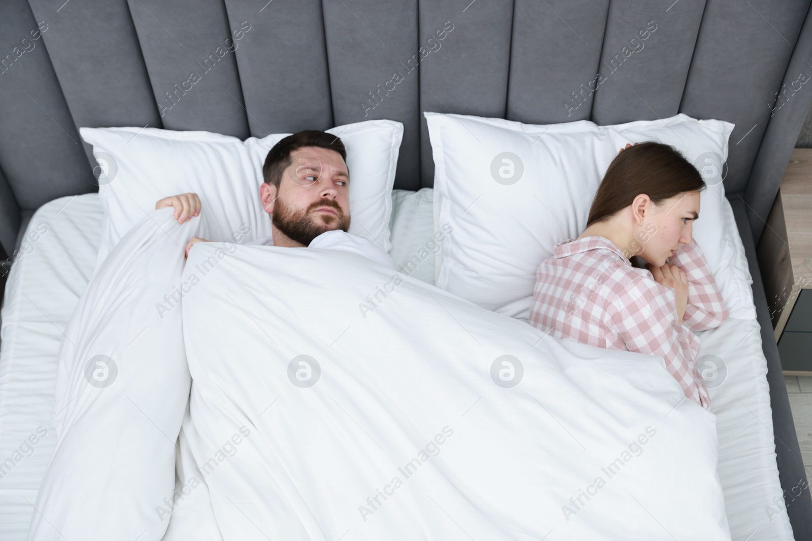 Photo of Resentful couple lying on bed at home, above view