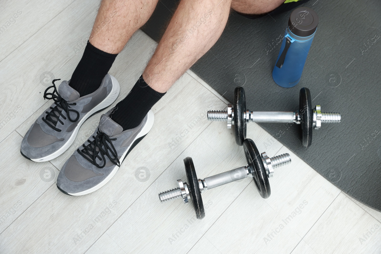 Photo of Man with bottle and barbells on floor indoors, above view