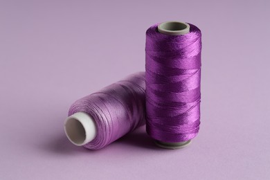 Photo of Spools of sewing threads on violet background, closeup