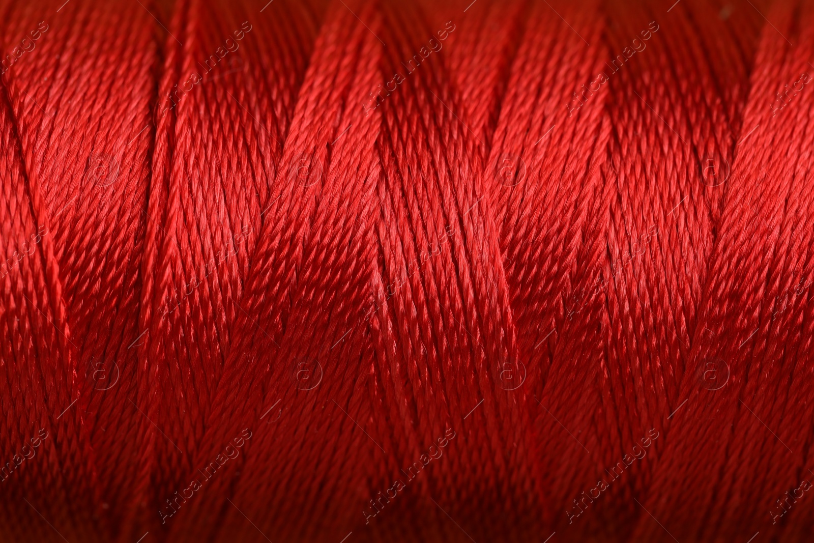 Photo of Spool of red sewing thread as background, closeup